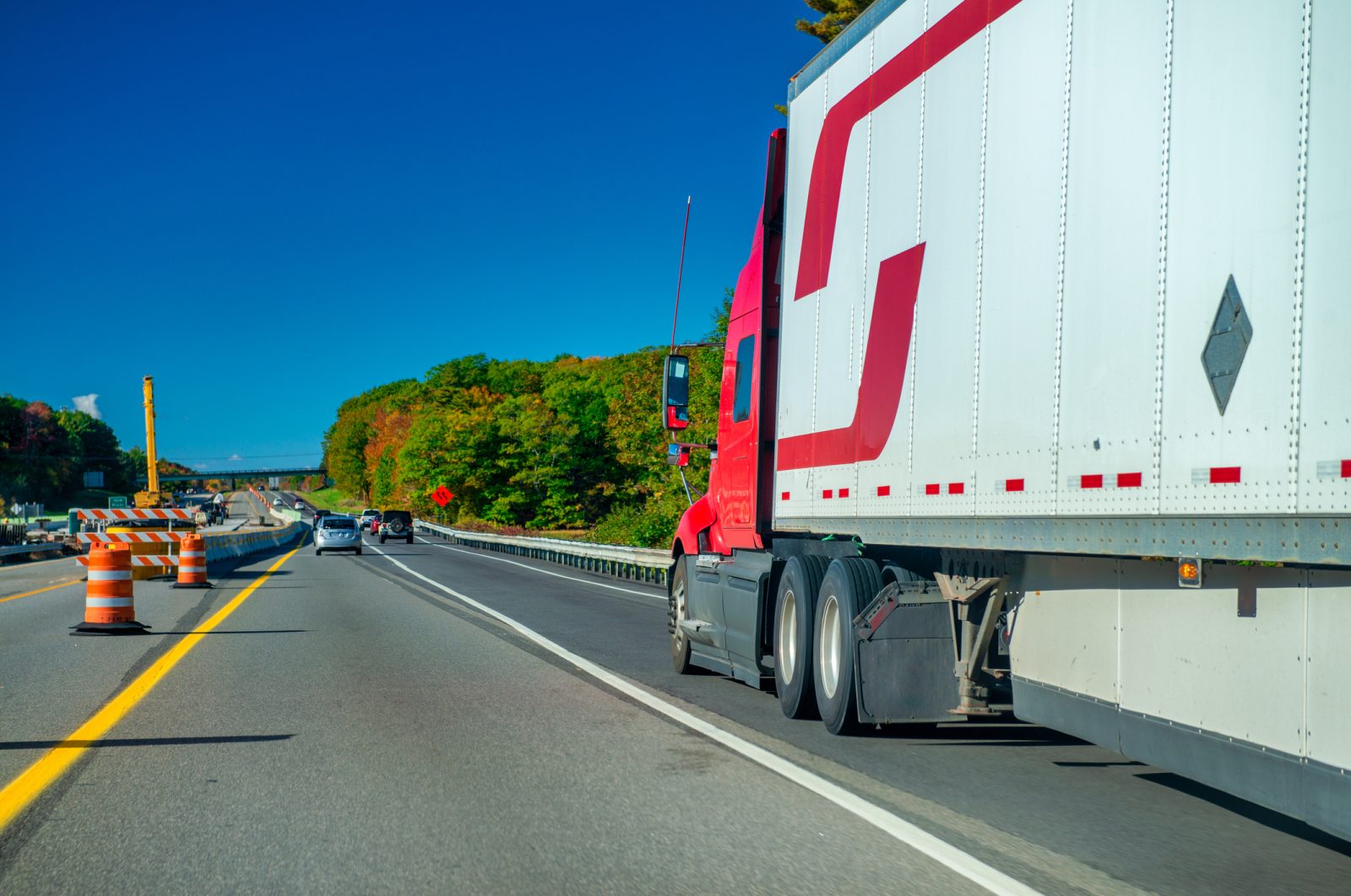 A tractor-trailer drives down the highway in Maine near passenger vehicles.
